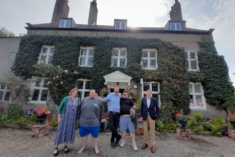 carer, supported person and MP stand outside the carer's 12-bedroom, 5 acre home
