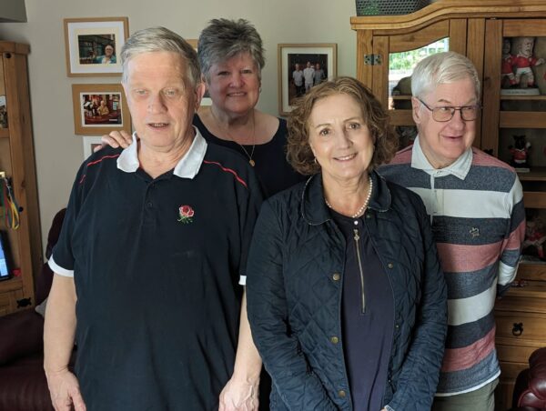 Pictured in the front room of Shared Lives carer are Medwyn and Gareth who are supported by Janet Smith pictured behind. Janet Finch Saunders MS is pictured in the foreground in between Medwyn and Gareth.