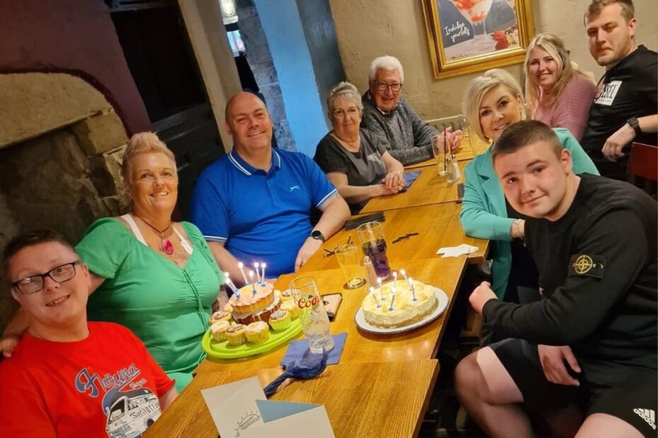 The whole family, including Phil who they support, their son Jayden and the grandparents are all gathered around a table together looking friendly and warm.