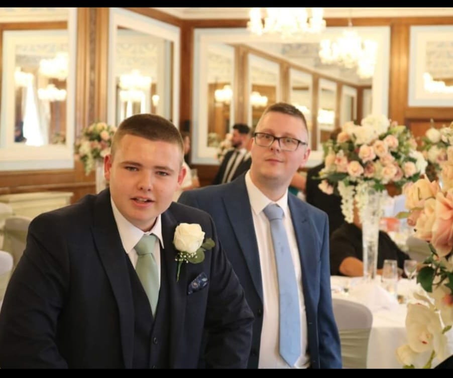 Phil and Jaydon ar elooking dapper in their suits because they were ushers at Paula's daughter's wedding. Phil wears glasses and a blue tie and navy suit and Jaydon wears a green tie, dark suit and a white rose on his lapel