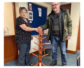 Trevor shakes hands with the local library worker after he donates his homemade hat stand to them