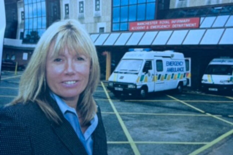 Janet is blonde and wearing a suit jacket, She is smiling at the camera in a friendly way. She's stood outside an A&E unit due to the nature of her work as a police officer back then.